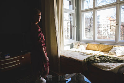 Woman standing on bed at home