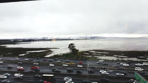 Cars on road by sea against sky