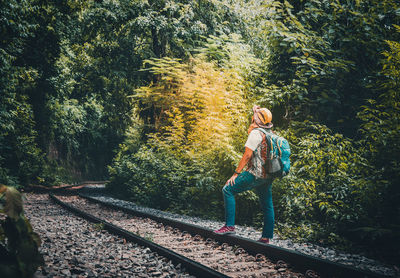 Man standing on railroad track amidst trees in forest