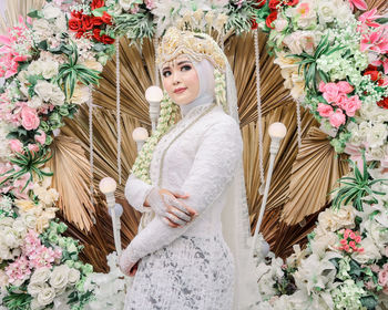 Portrait of woman standing by flower plants