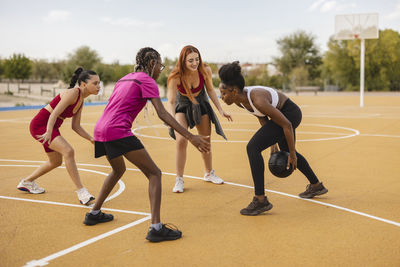 Young woman with friends playing basketball at sports court