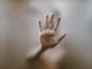 Close-up of person hand on glass window