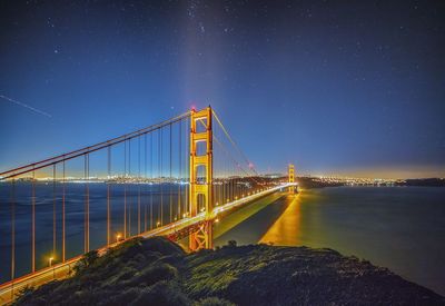 Illuminated bridge against sky at night