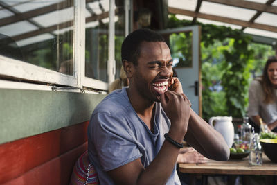 Man laughing while enjoying party with friend at log cabin