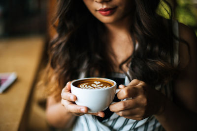 Midsection of woman holding coffee cup in cafe