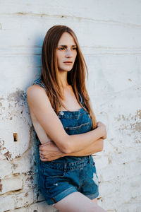 Portrait of beautiful young woman against wall