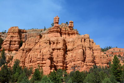 Low angle view of rocky mountain against blue sky