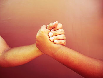 Cropped image of men arm wrestling against wall