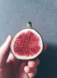 Cropped hand holding fig on table