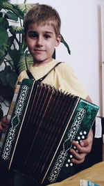 Portrait of cute boy playing harmonium at home