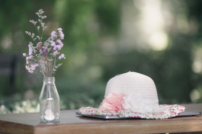 Hat that sits on my laptop on a table wooden and flower vase is my workspace in my garden house stay 