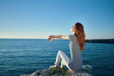 Woman by sea against clear blue sky