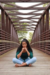 Portrait of young woman sitting on bridge