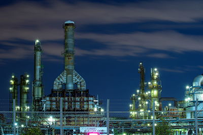 Illuminated factory against sky at night