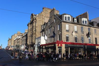 People in front of buildings against blue sky