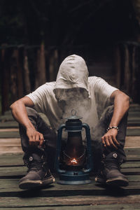 Midsection of man holding an oil lamp and smoking vape