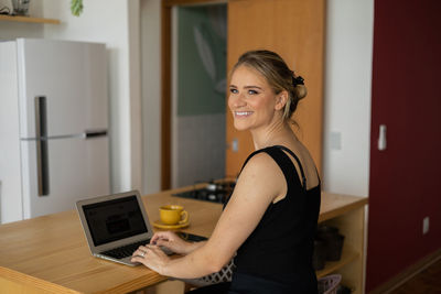 Portrait of young woman using laptop at home