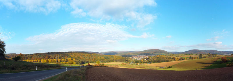 Scenic view of road by mountains against blue sky