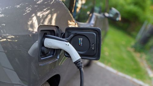 Close-up of electric vehicle charging against a green background