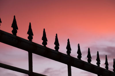 Low angle view of metallic fence against sky