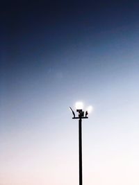 Low angle view of illuminated floodlights against clear sky