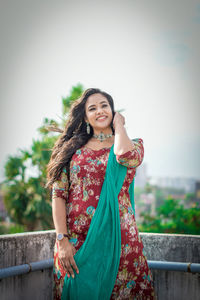 Portrait of young woman standing against sky