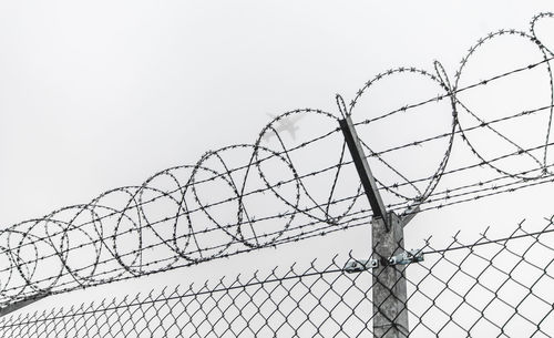 Low angle view of barbed wire fence against clear sky