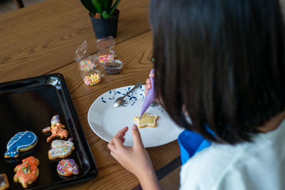 High angle view of girl icing cookies