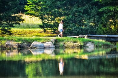 Reflection of child in lake against trees