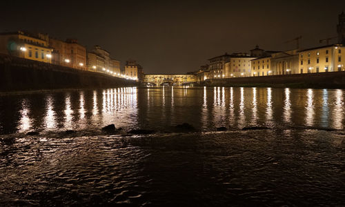 View of illuminated buildings by river at night