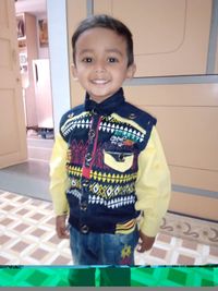 Portrait of smiling boy standing against wall