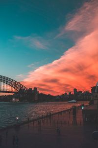 Bridge over river against cloudy sky during sunset