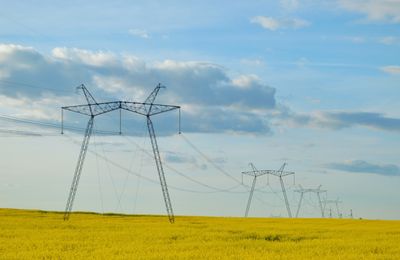 Low angle view of electricity pylon on field against sky