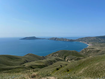 Scenic view of sea and mountains against clear blue sky