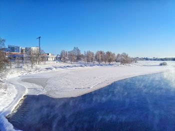 Scenic view of frozen lake against clear blue sky