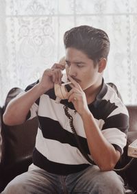 Man smoking cigarette while talking on phone at home