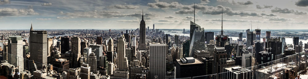 Panoramic view of skyscrapers against cloudy sky