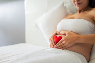 Midsection of woman relaxing on bed