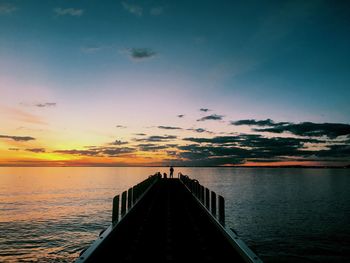 Pier on sea at sunset