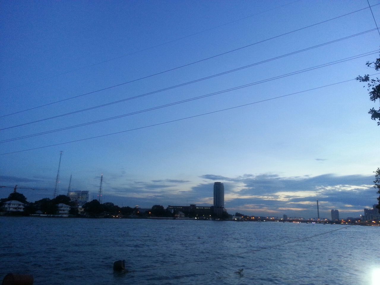 power line, connection, electricity pylon, cable, electricity, built structure, sky, architecture, water, power supply, building exterior, blue, river, fuel and power generation, waterfront, city, silhouette, power cable, outdoors, no people