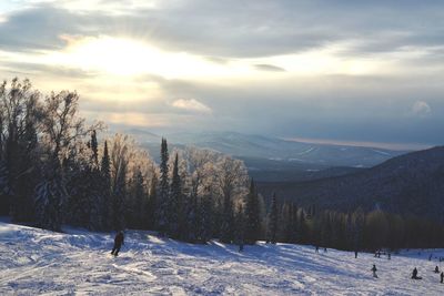 People skiing on snow covered field against sky during sunny day