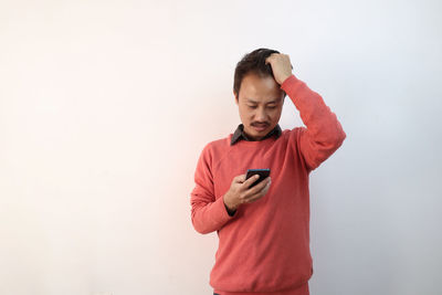 Young man using mobile phone against white background