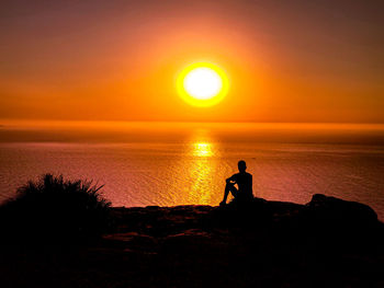 Silhouette man on beach against sky during sunset