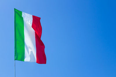 Low angle view of italian flag waving against clear blue sky