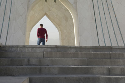 Tehran, iran - 7 may 2018 young man walking under azadi tower formerly known as the shahyad tower
