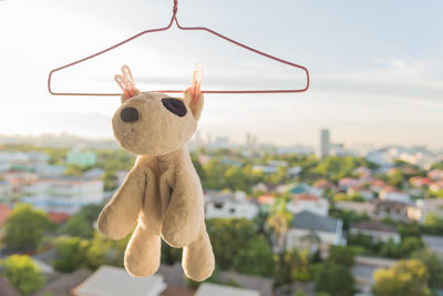 Close-up of stuffed toy hanging on coathanger against sky