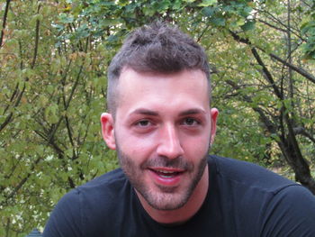 Portrait of smiling young man against trees