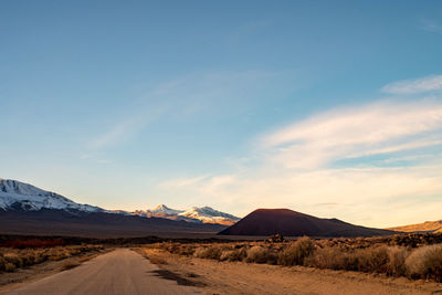 Road leading towards mountains against sky