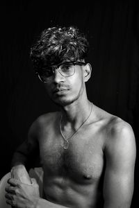 Portrait of shirtless young man against black background