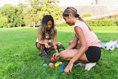 Mother and daughter playing boules crouching on grass